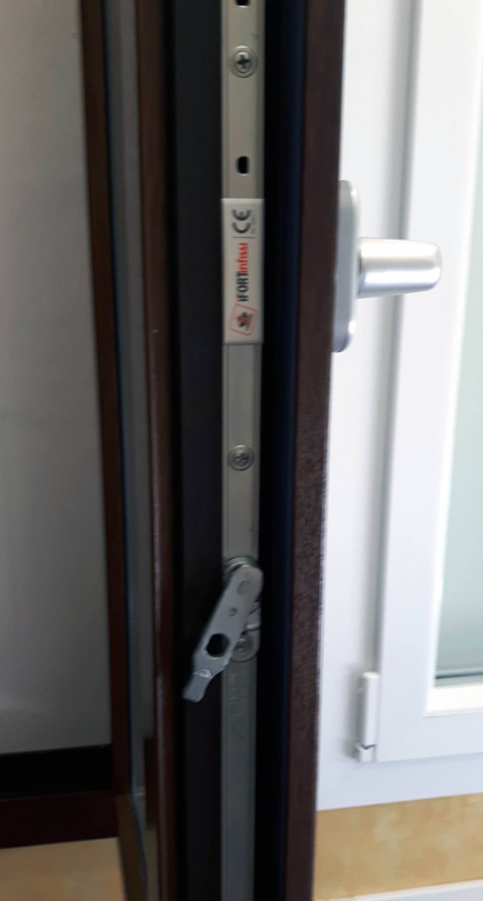 Primo piano di una serratura e della maniglia di una porta su un telaio bianco con bordo in legno scuro.