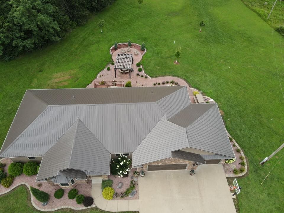 Aerial view of a gray-roofed house with a landscaped yard and green lawn.