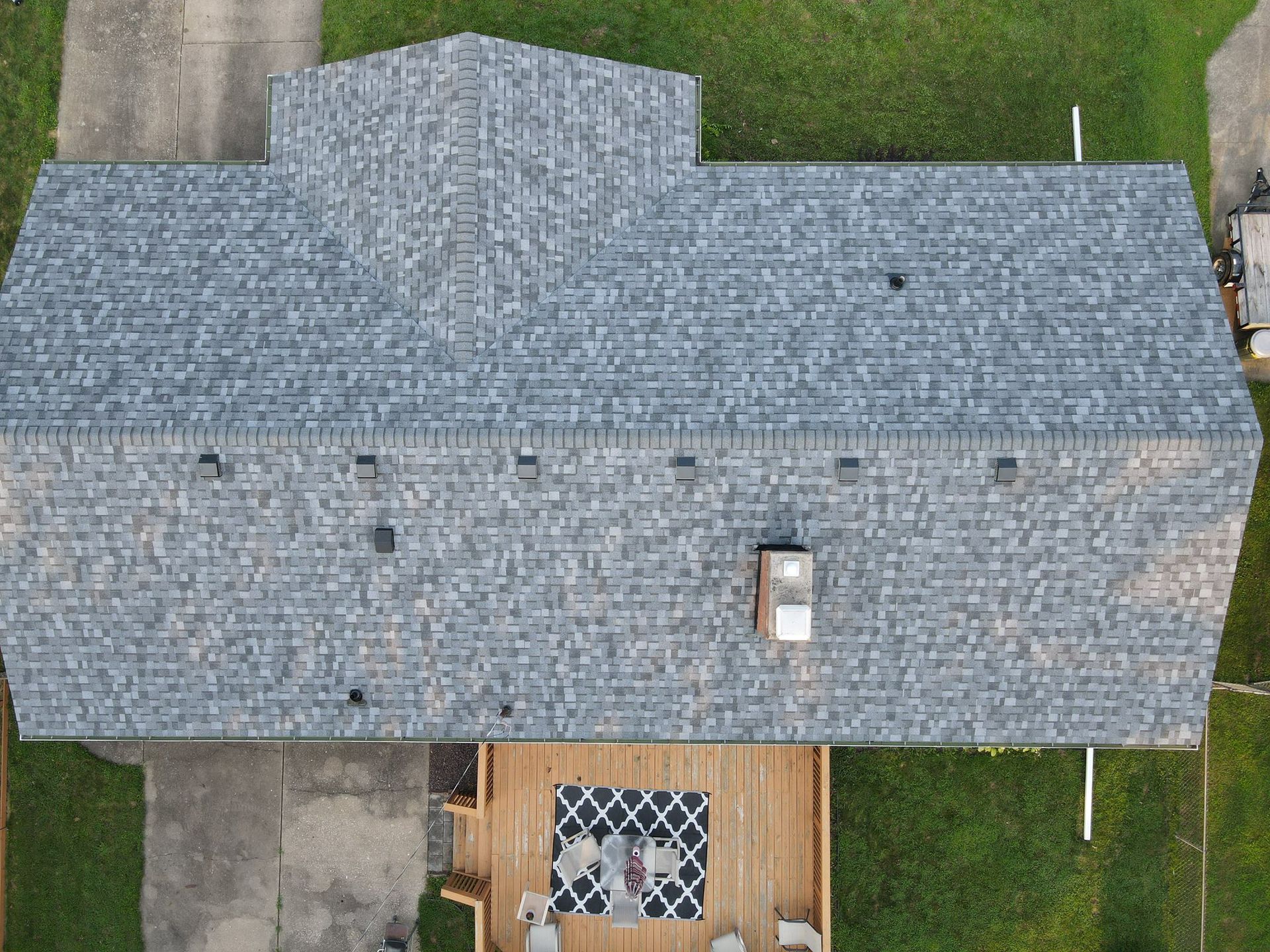 Aerial view of a house with a gray shingled roof and small front porch.