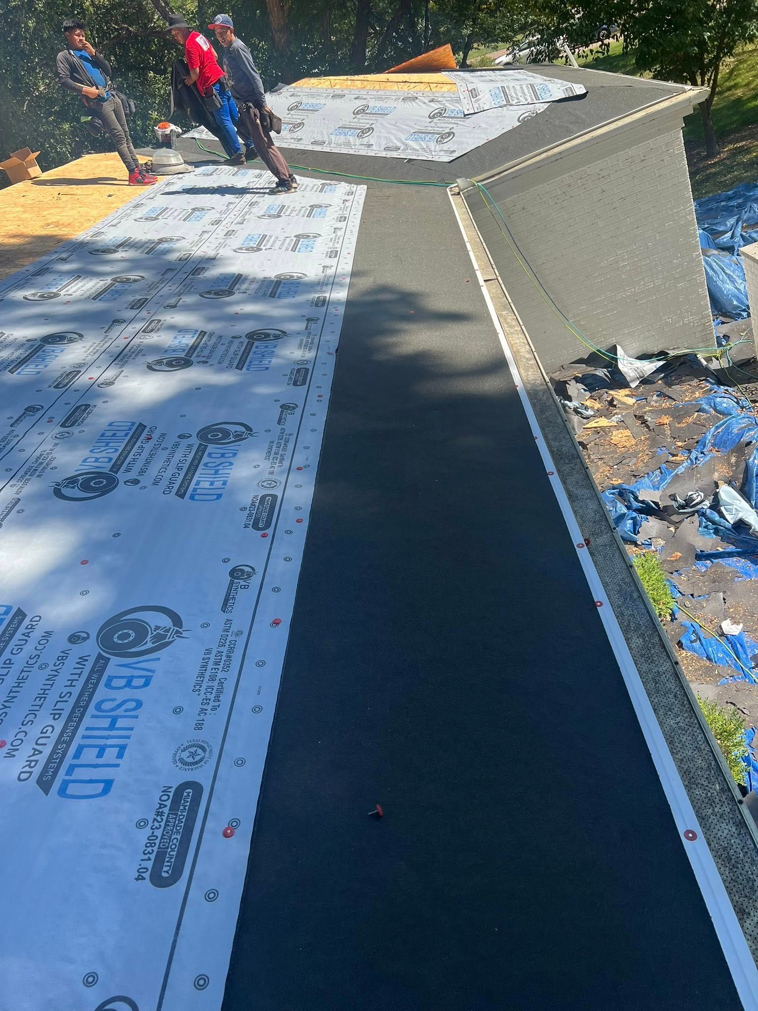 Workers installing white roofing panels on a roof under construction
