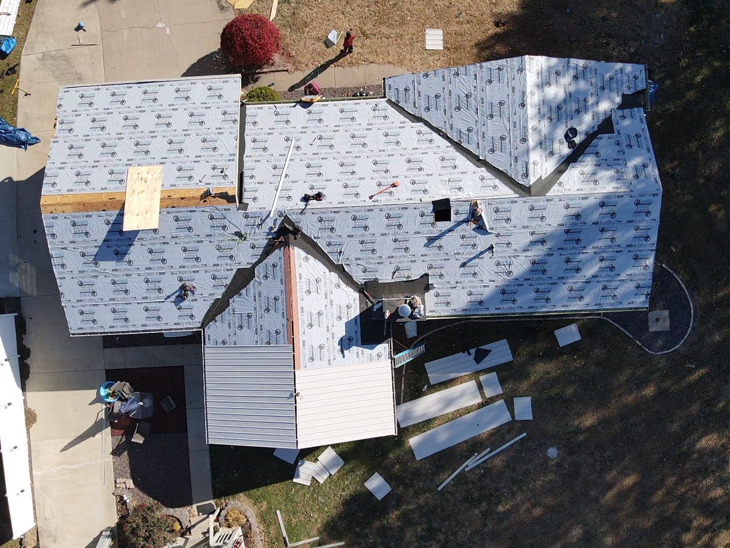 Aerial view of a house with a gray shingled roof and a small covered patio below.