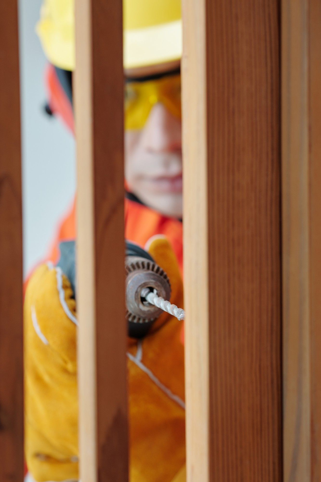 a man wearing a hard hat and safety glasses is working on a wooden fence