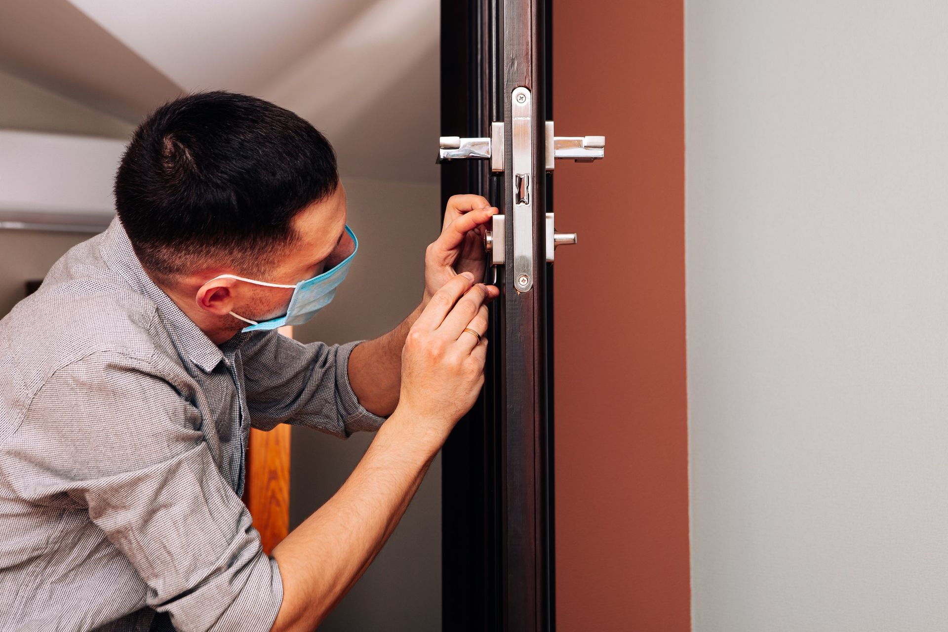 a man wearing a mask is fixing a door lock