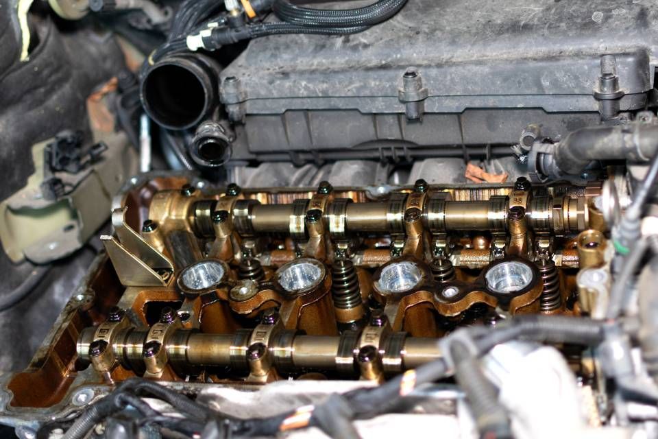Close-up of exposed car engine valve train with camshaft and metal components visible