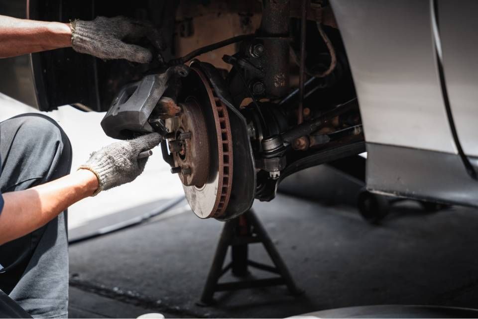 Mechanic removing a car's brake rotor while the vehicle is raised on a jack
