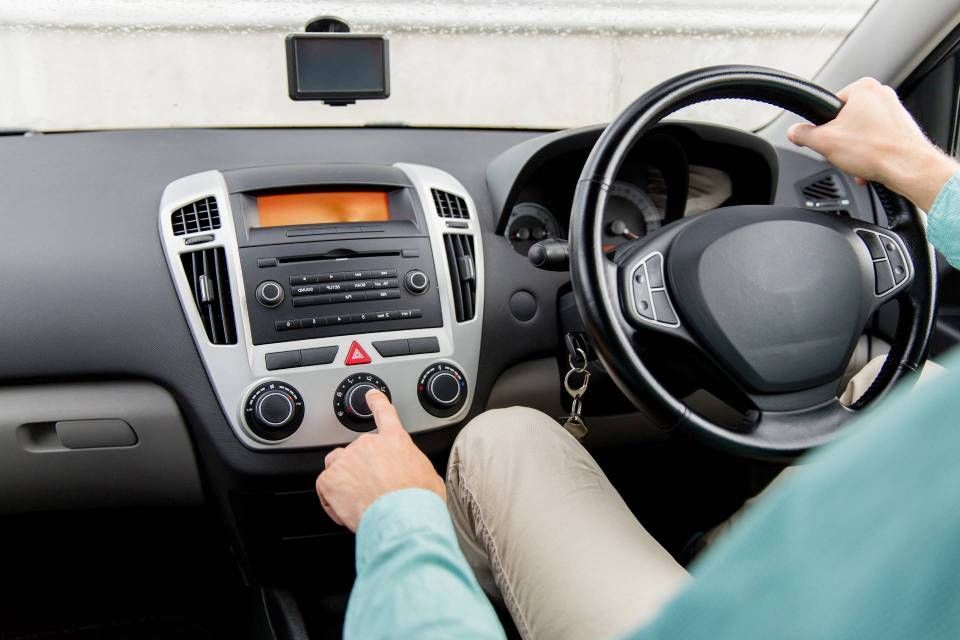 Person driving car, adjusting the center console controls on a dashboard with orange display.