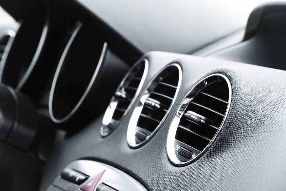 Close-up of silver car dashboard air vents and textured interior trim