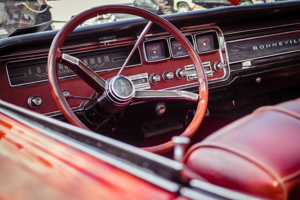 Classic red convertible interior with a wood steering wheel and chrome dashboard details