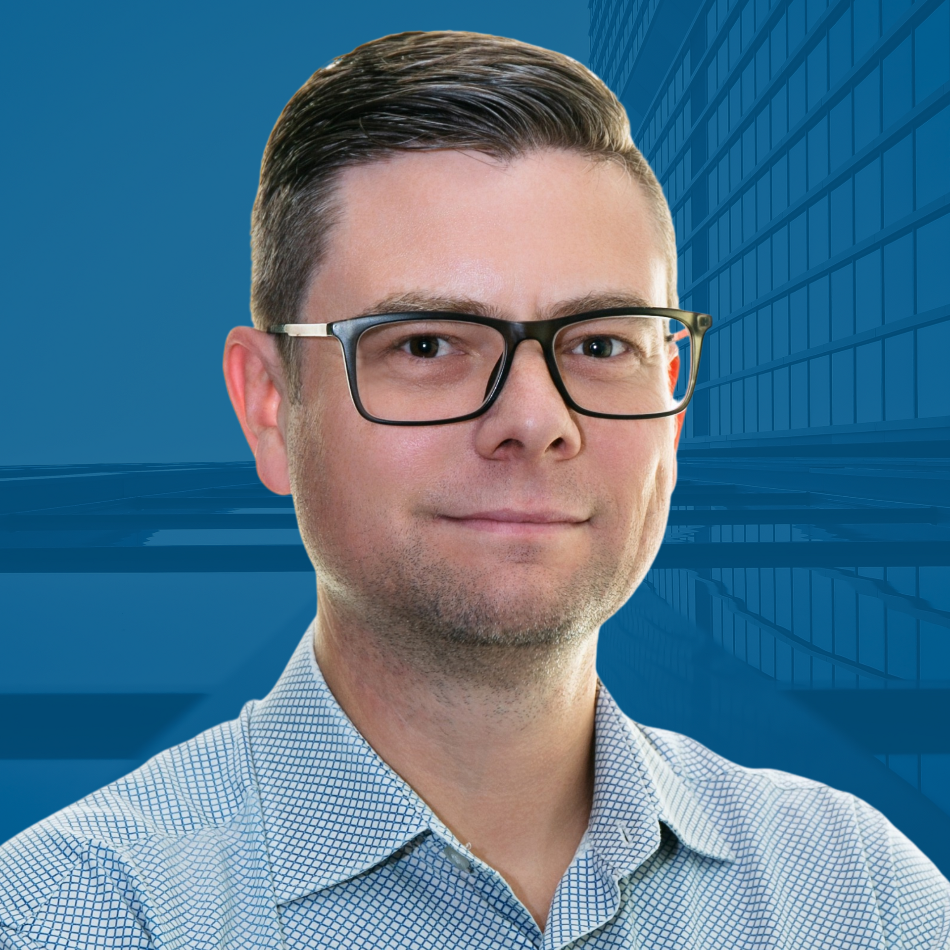 Man wearing glasses and button-down shirt, smiles in front of a blue background with a building.