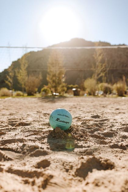 Blue golf ball on sandy ground with sunlit hills in the background