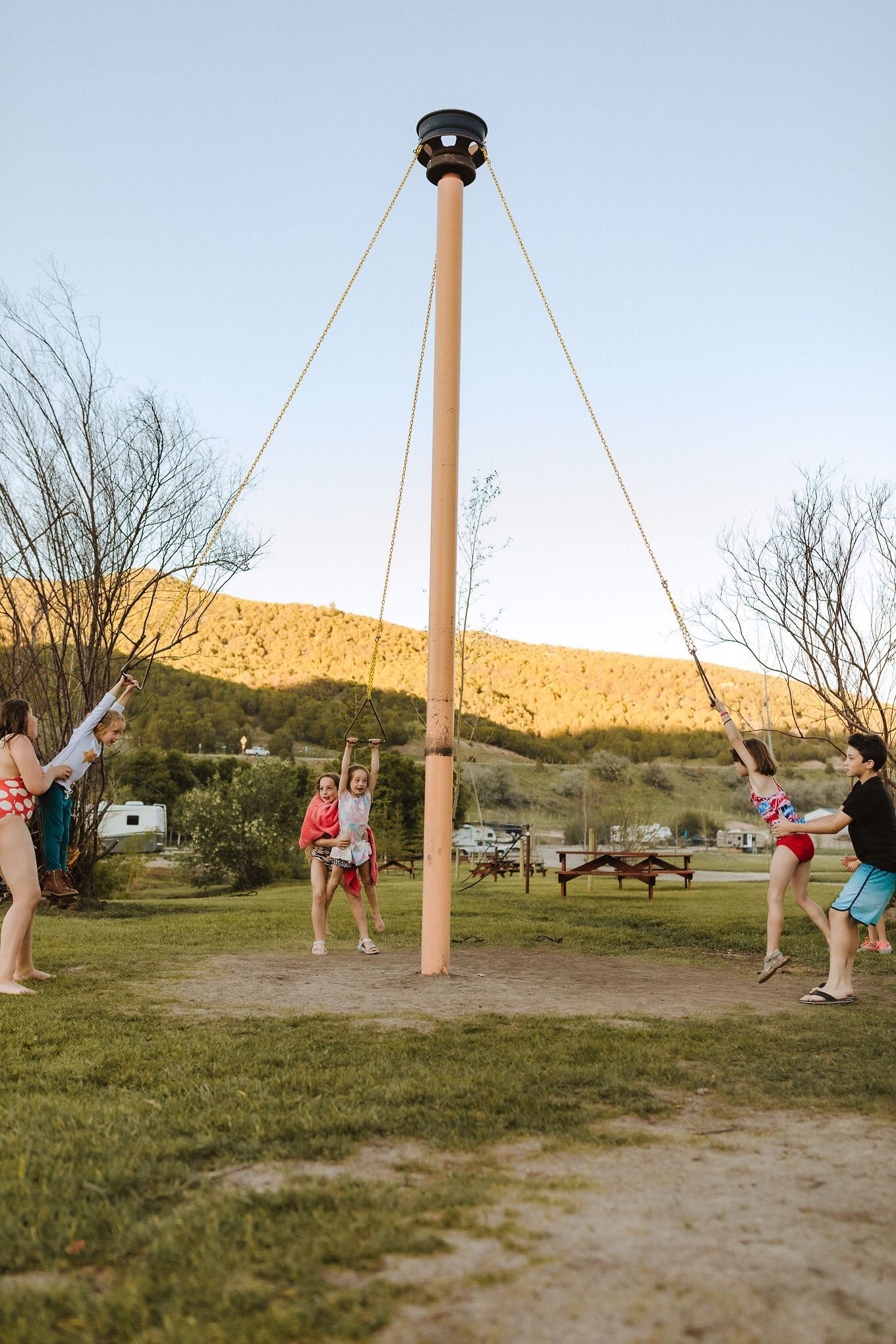People on a tall swing ride in a grassy outdoor park at dusk