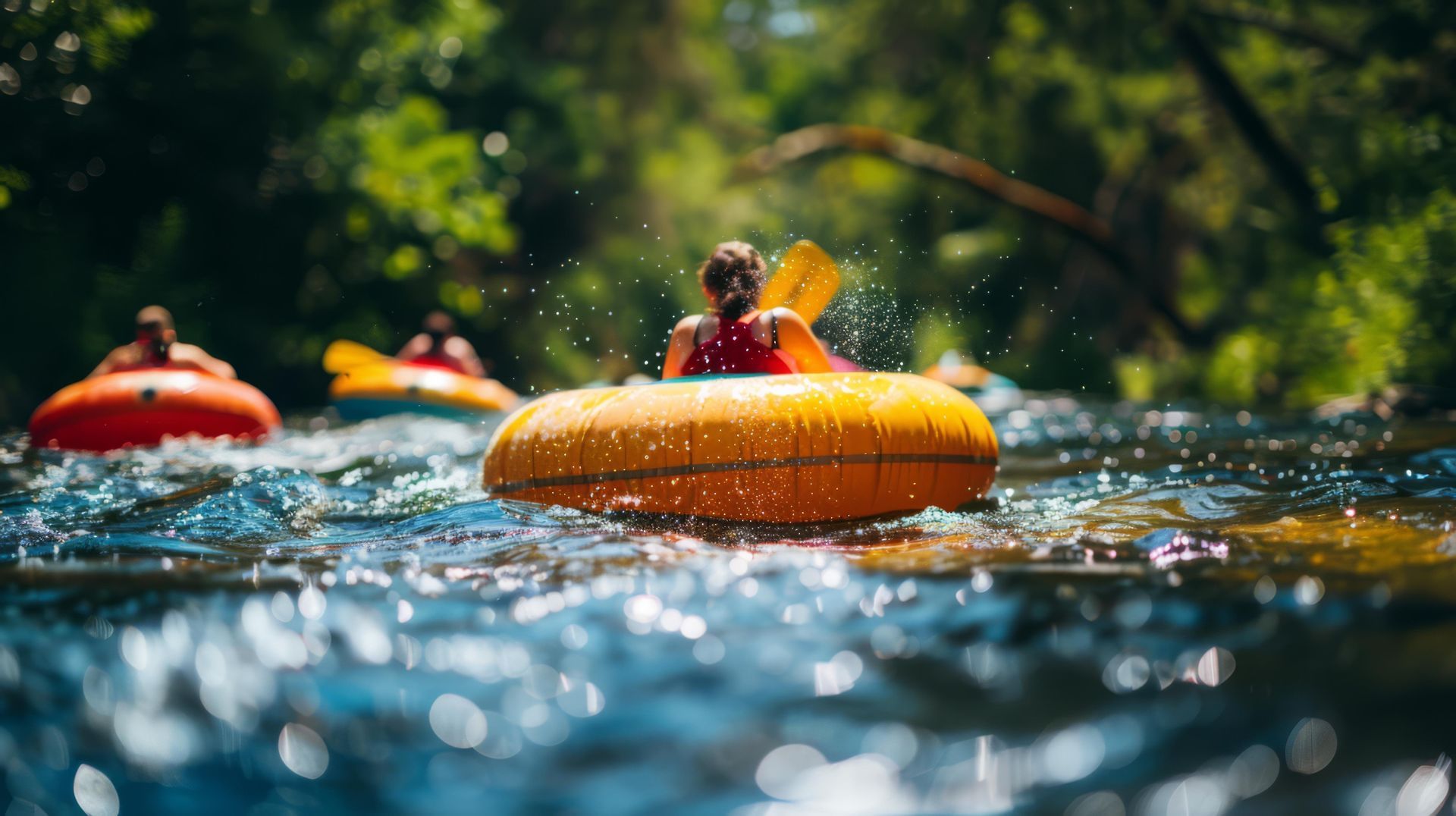 People tubing down a river, with colorful inflatable tubes splashing through water under greenery