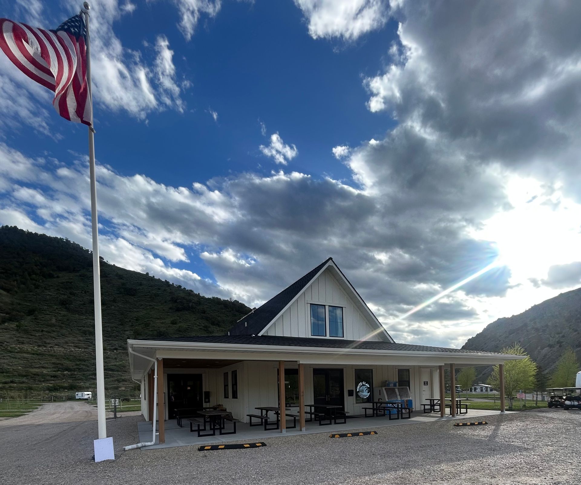 Flagpole and rustic building in a mountain valley under a dramatic cloudy sky