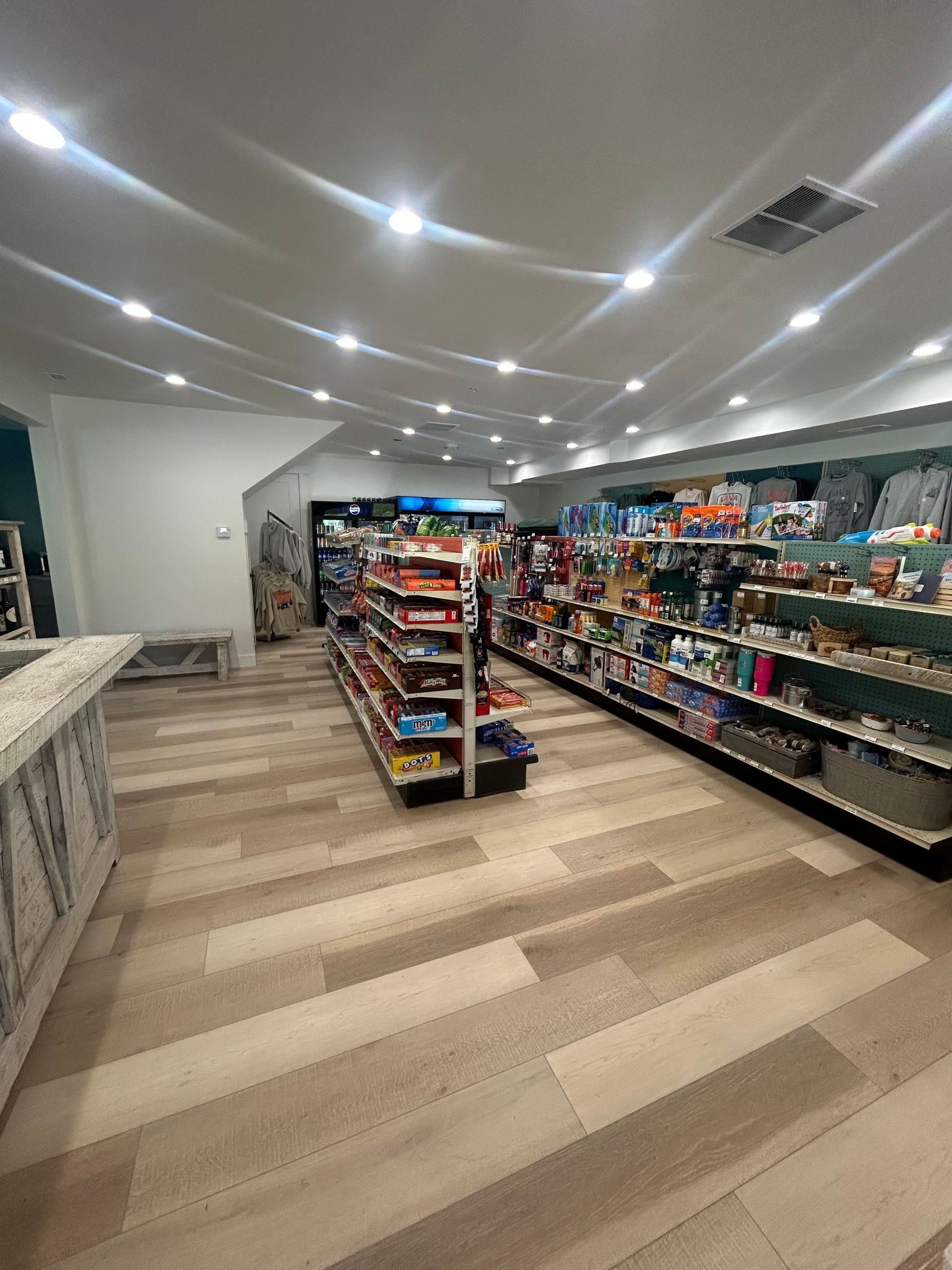Bright convenience store aisle with shelves of snacks and drinks under recessed ceiling lights.