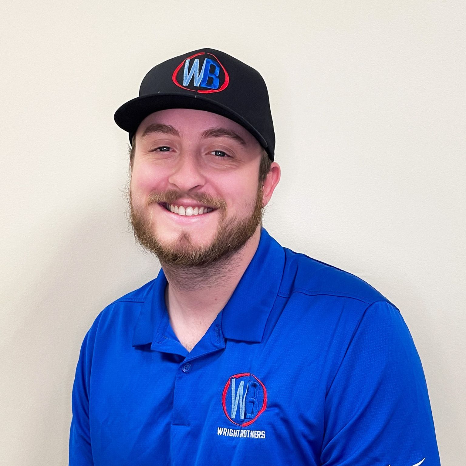 A man wearing a blue shirt and a black hat is smiling for the camera.