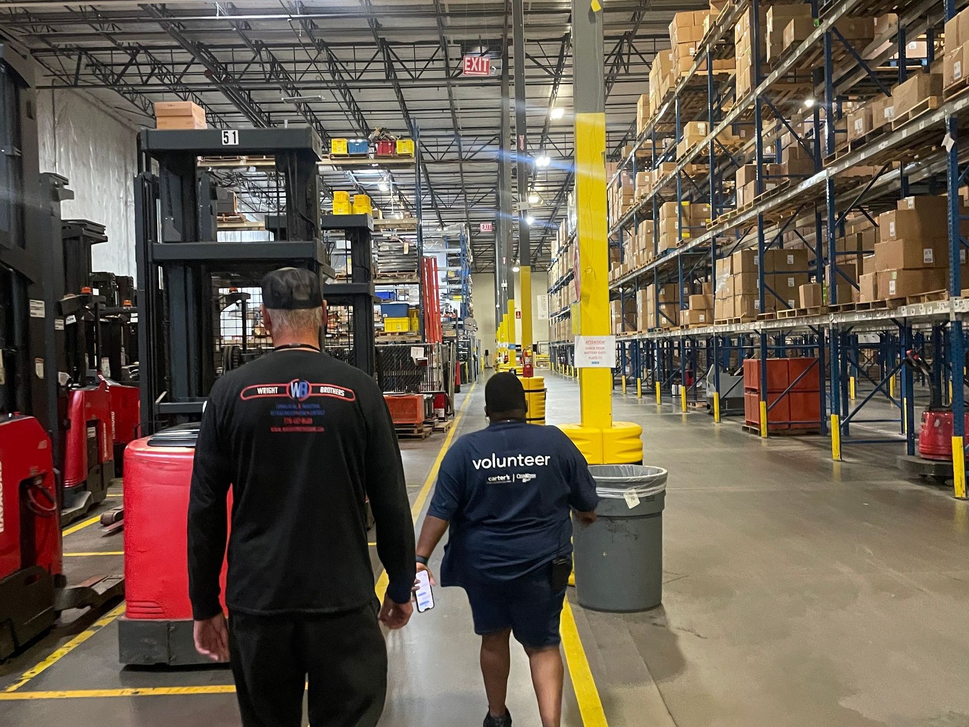 A man and a woman are walking through a large warehouse.