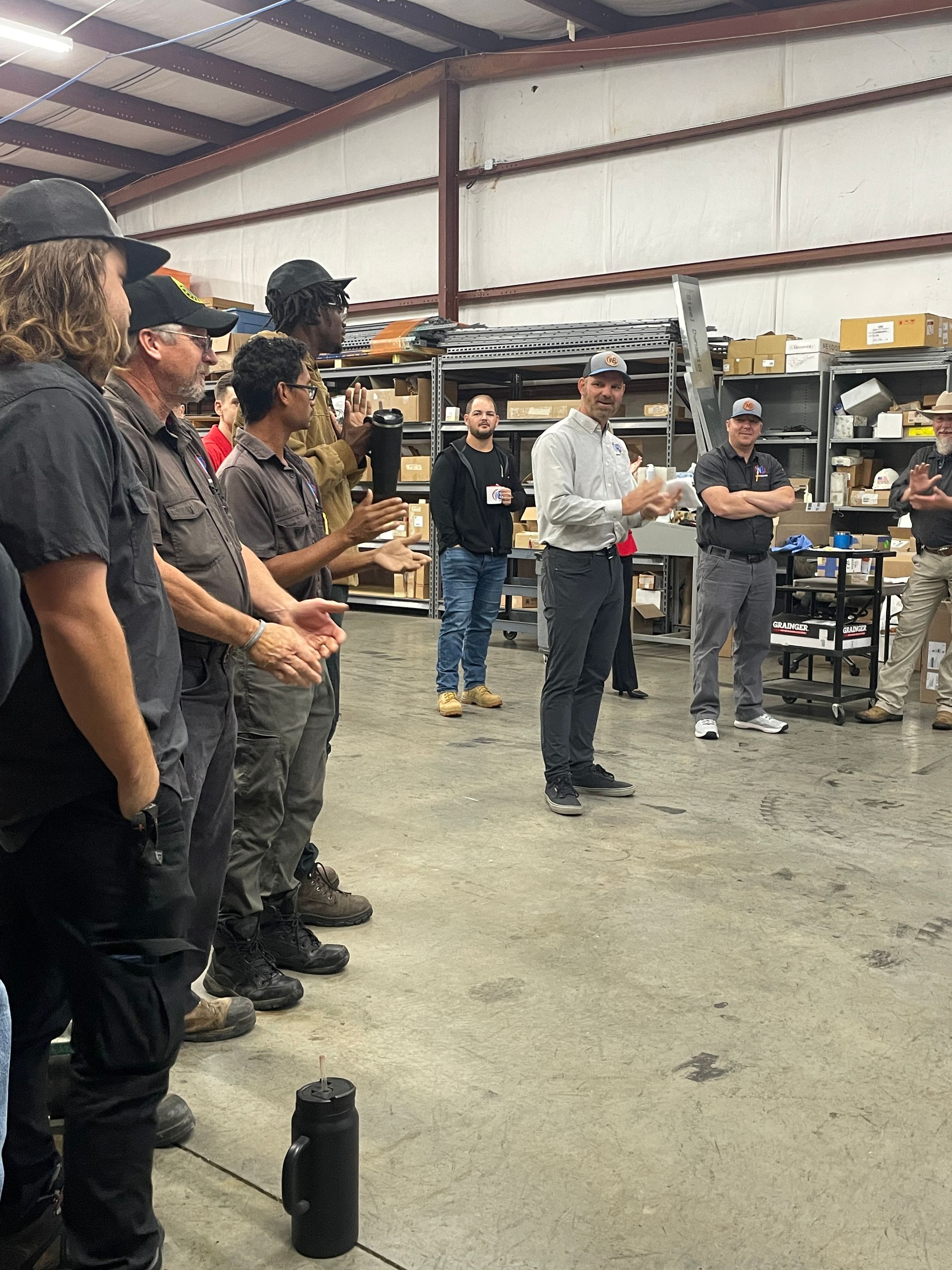 A group of men are standing in a warehouse talking to each other.