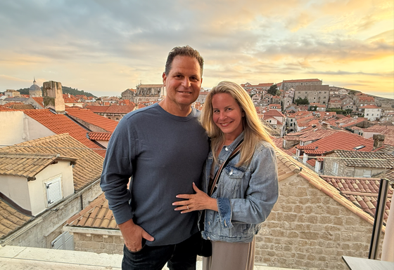 Couple standing on a rooftop terrace overlooking a historic city at sunset
