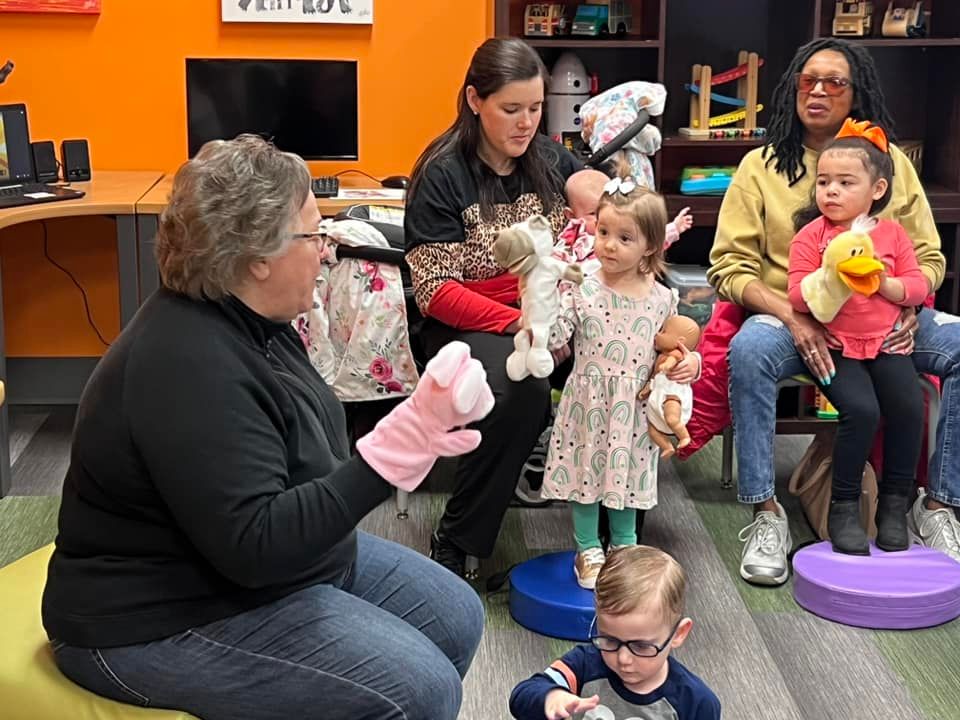 A woman showing a puppet to a child