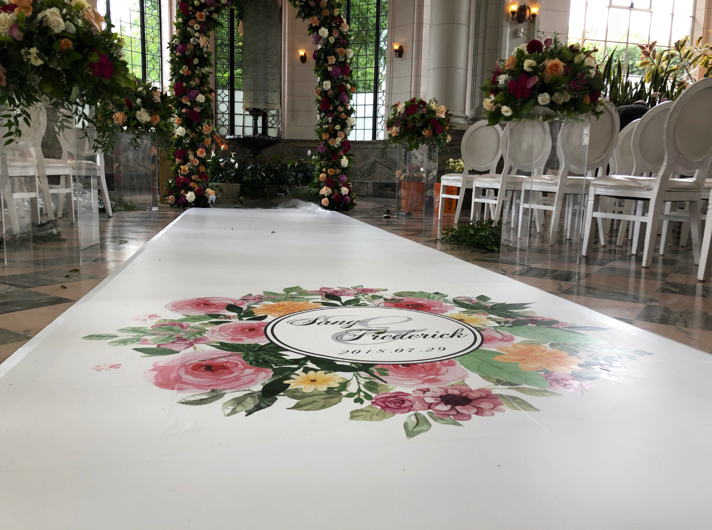 A wedding ceremony is taking place in a room with a floral design on the floor.
