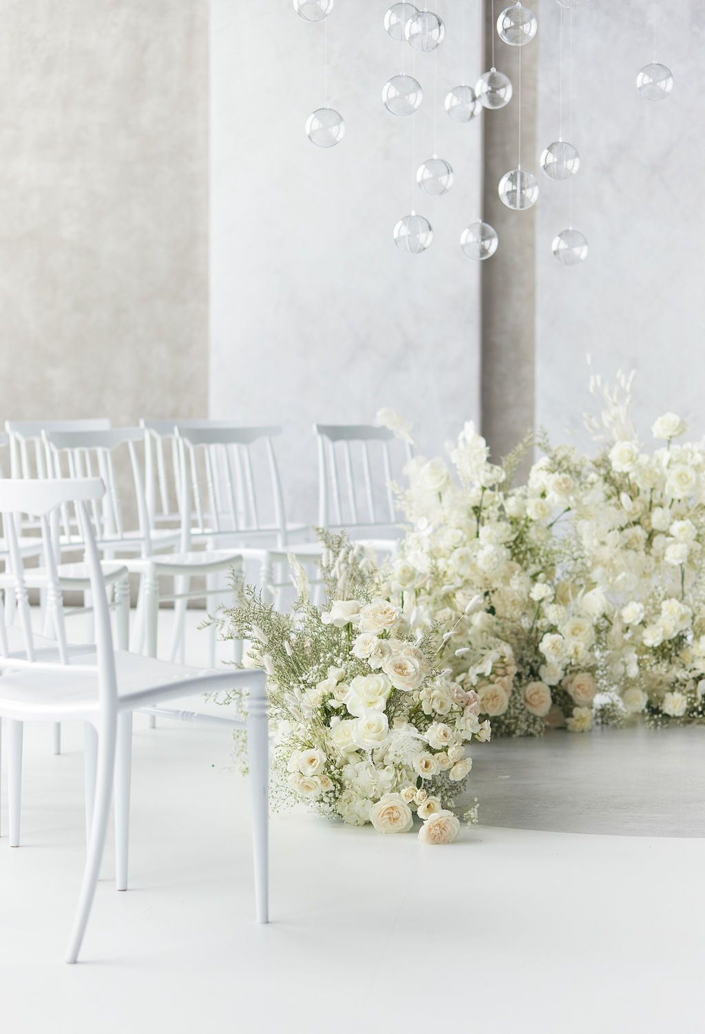 A row of white chairs sitting next to a row of white flowers.