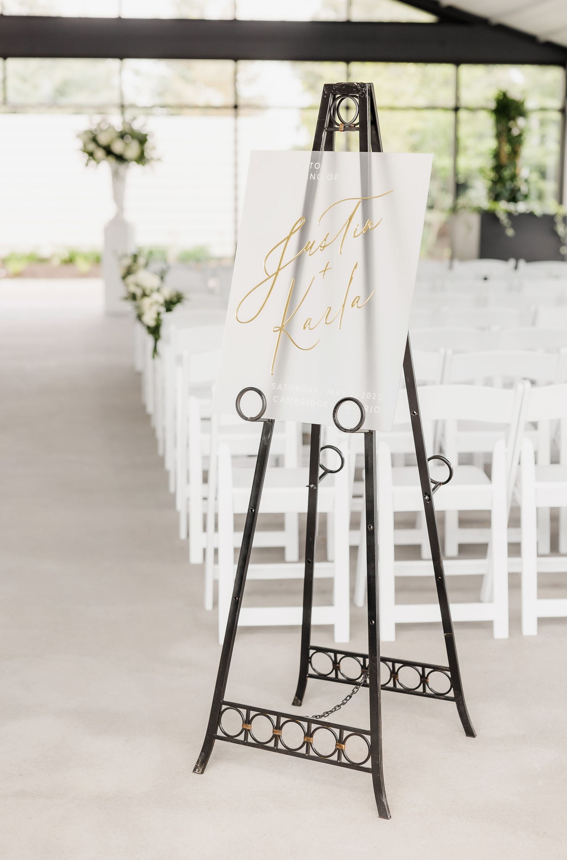 A sign on an easel in front of a row of white chairs.