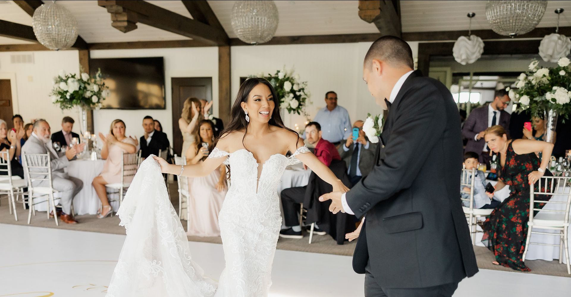 A bride and groom are dancing on a white dance floor at their wedding reception.