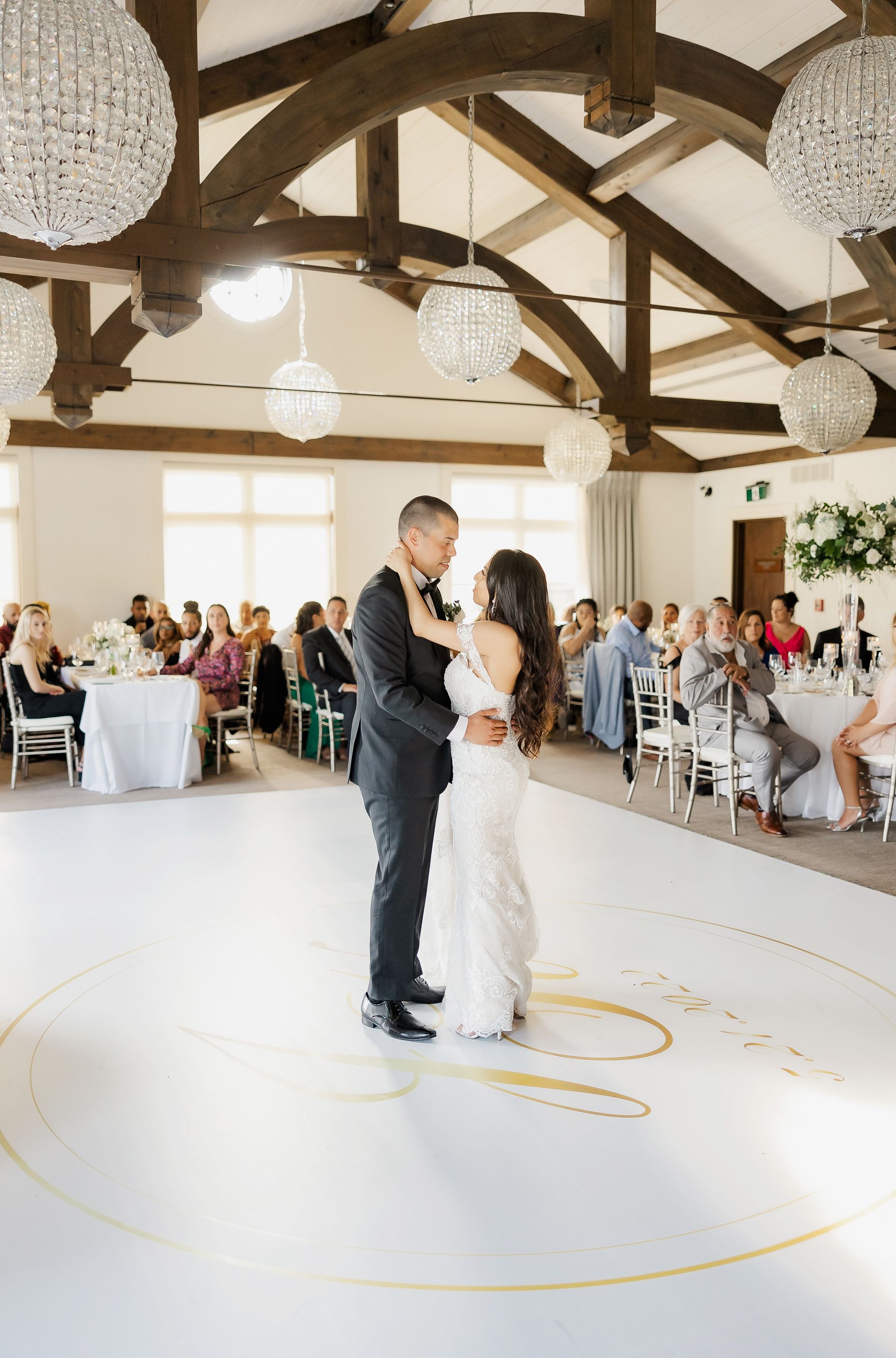 A bride and groom are dancing on a white dance floor at their wedding reception.