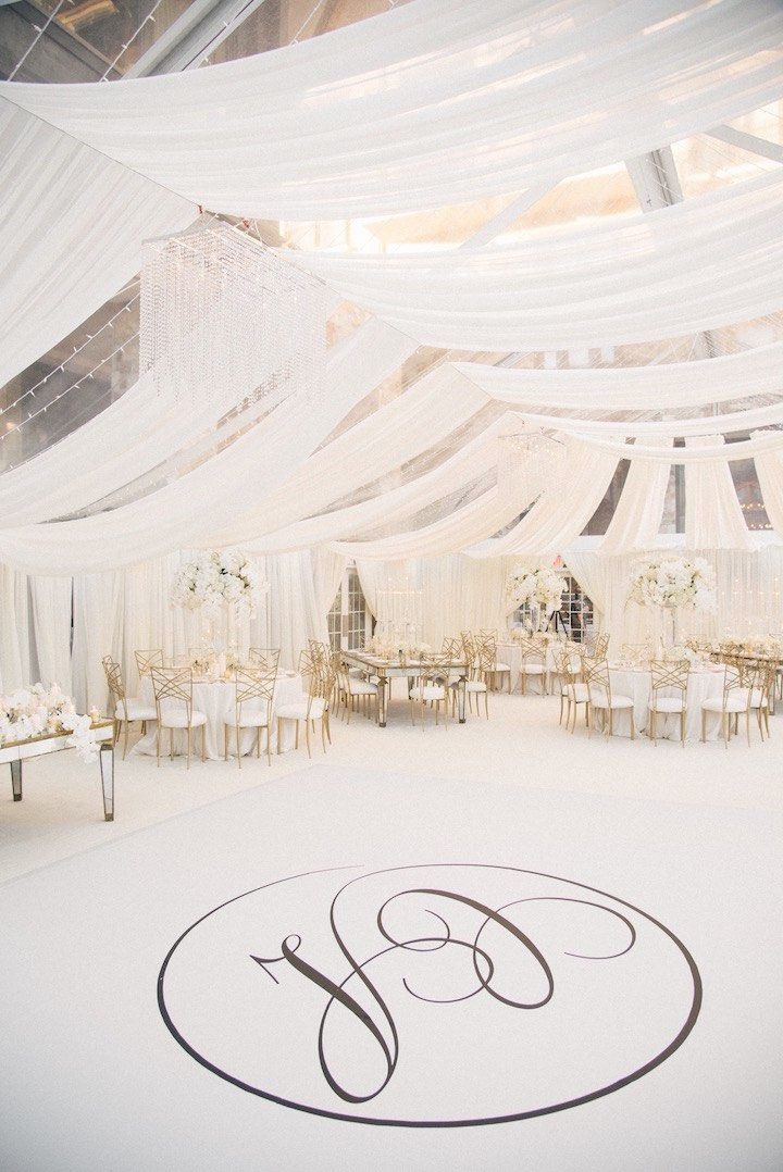 A large white tent with a monogram on the floor.