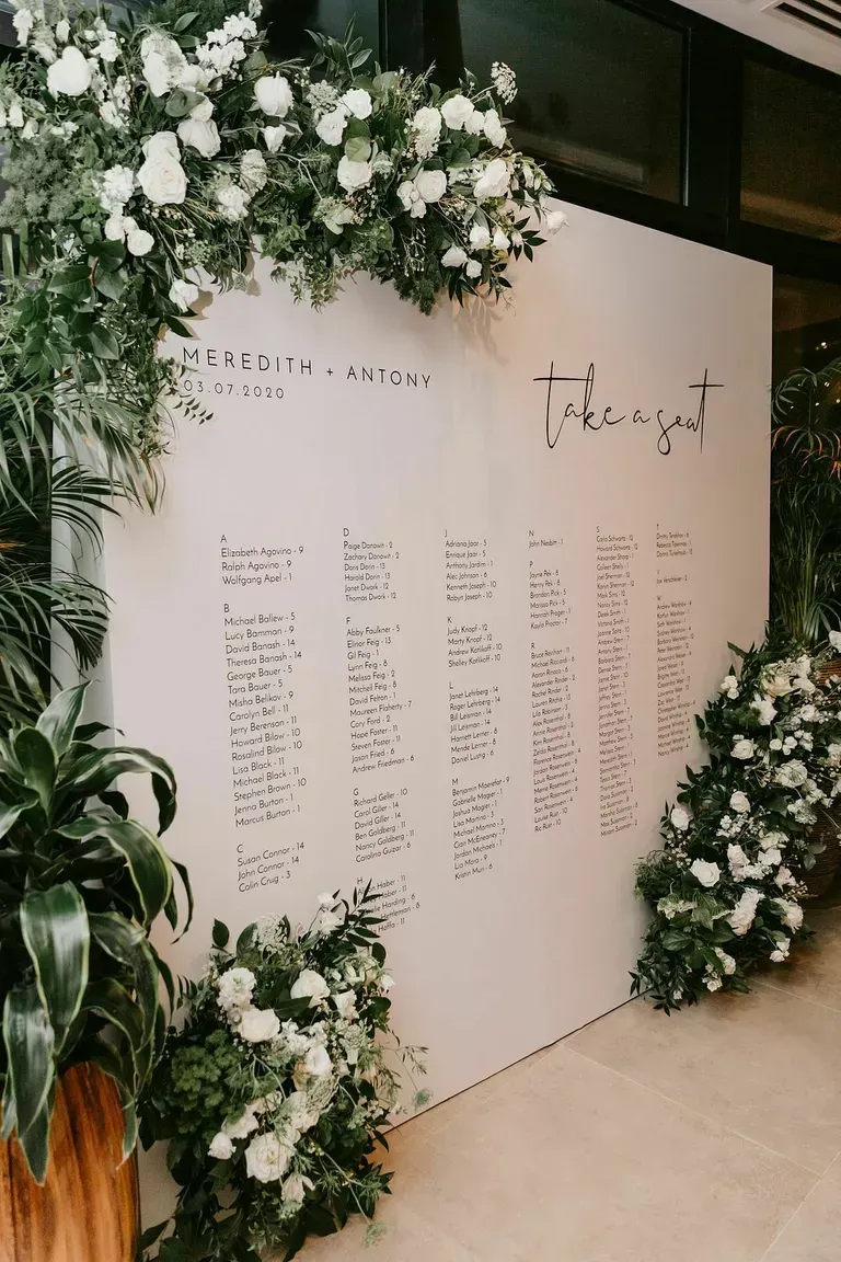 A white wall covered in white flowers and greenery.
