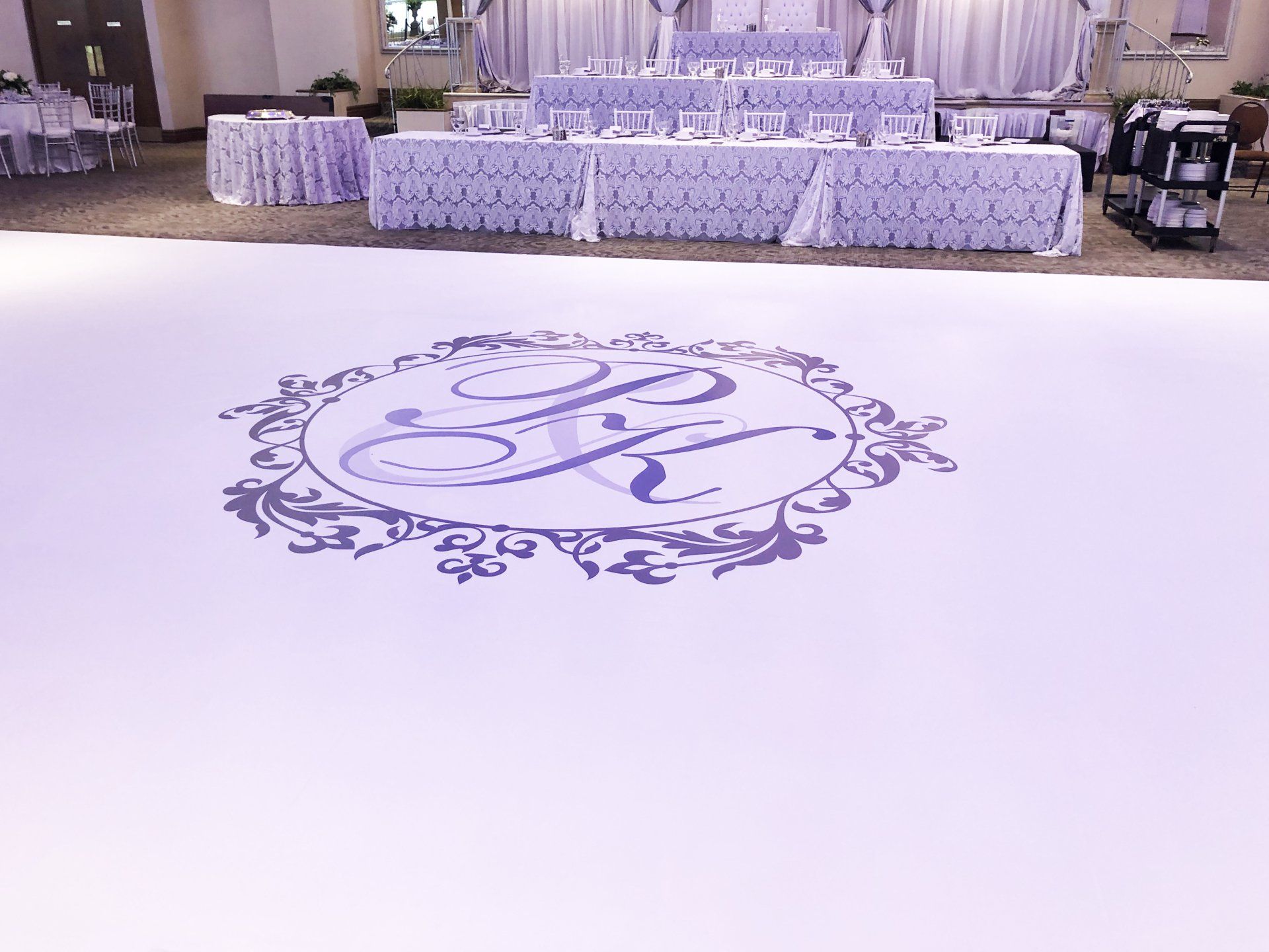 A white dance floor with a purple monogram on it.