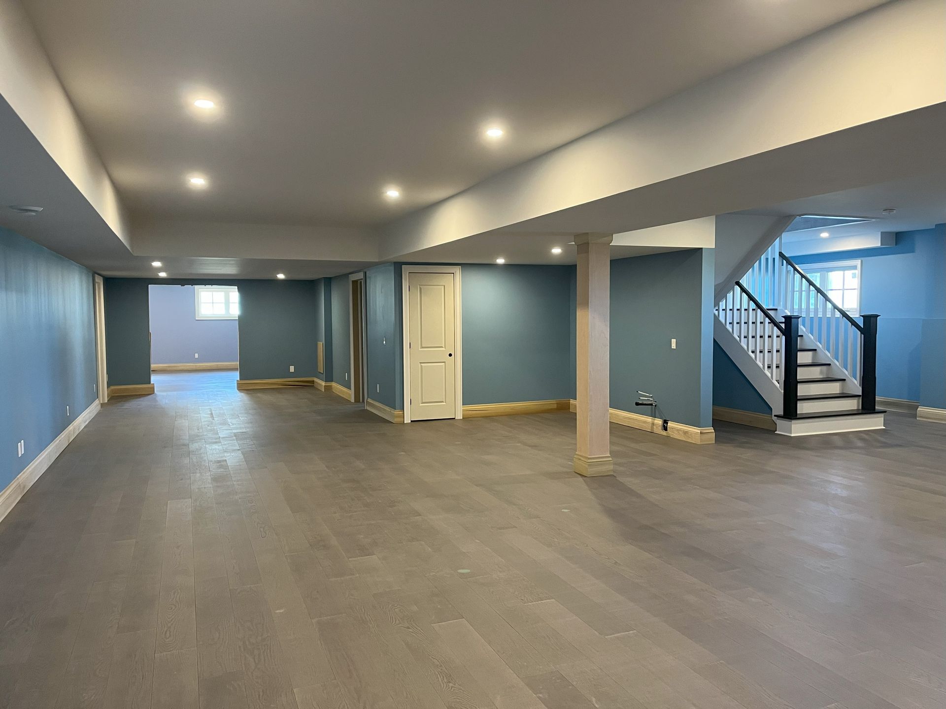 An empty basement with blue walls and stairs.