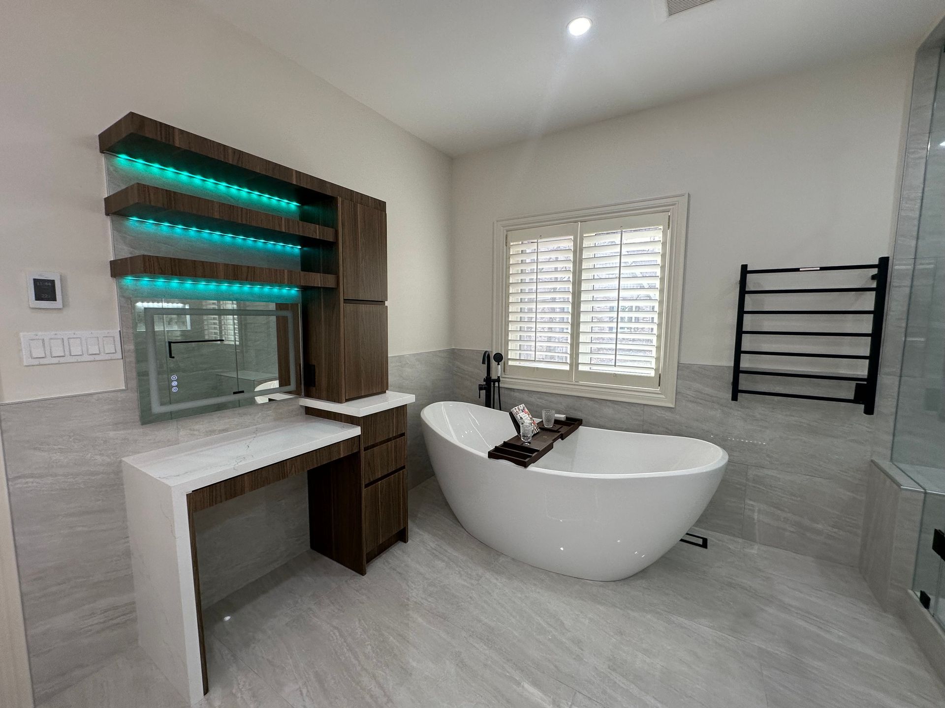 A bathroom with a bathtub , vanity , mirror and window.