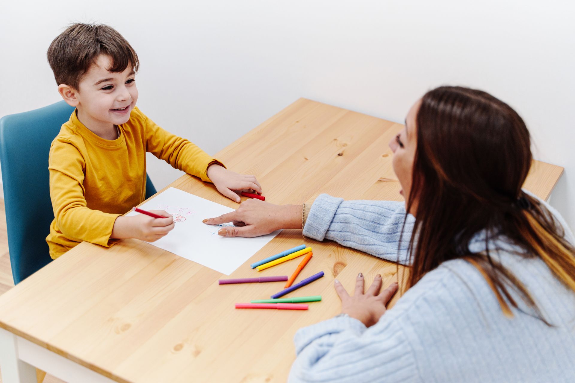 A woman is sitting at a table with a child.