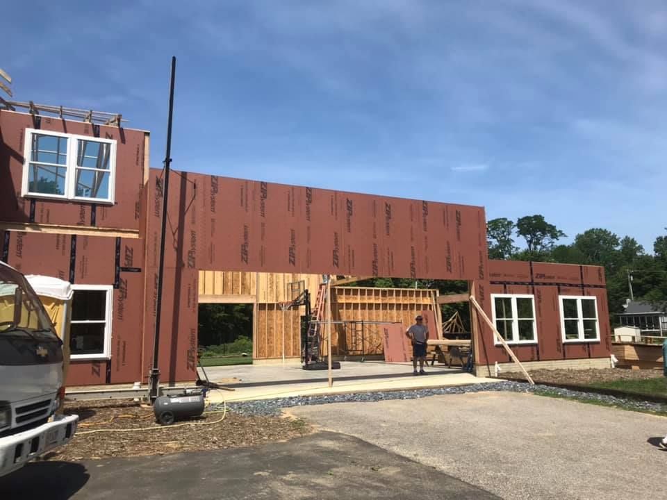 Modern building facade under construction with rust-colored panels and open framing, viewed from a paved lot