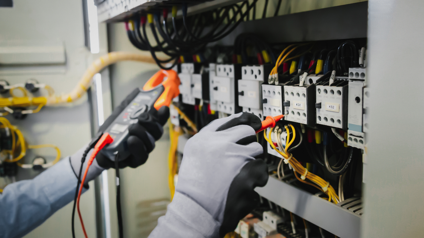 Technician using insulated tools to repair electrical wiring in a control panel