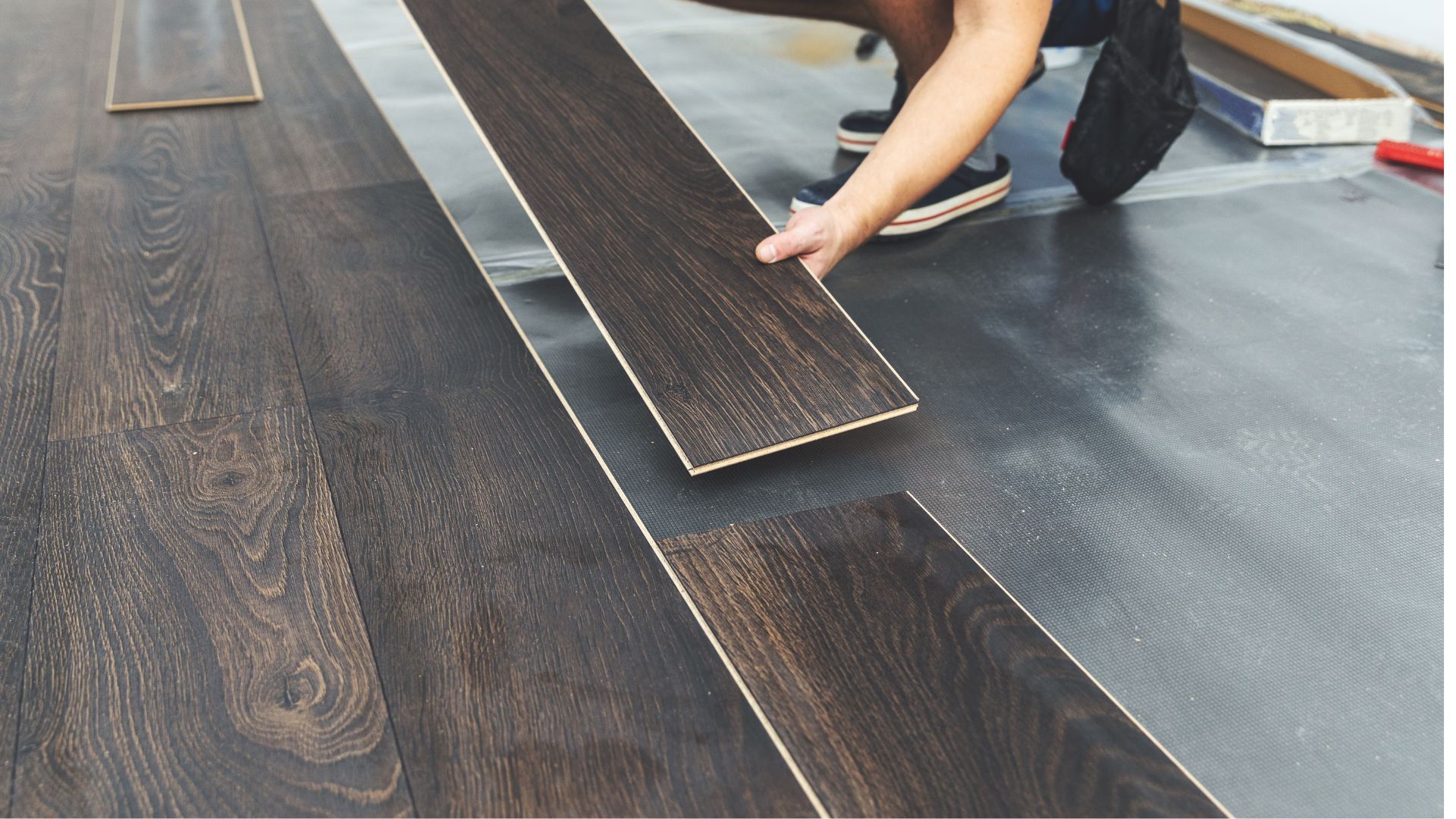 A person is installing a wooden floor in a room.