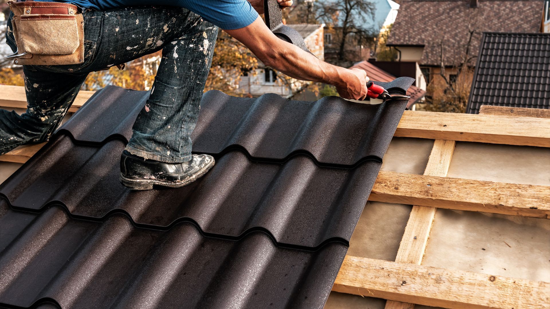 A man is kneeling on top of a roof working on it.