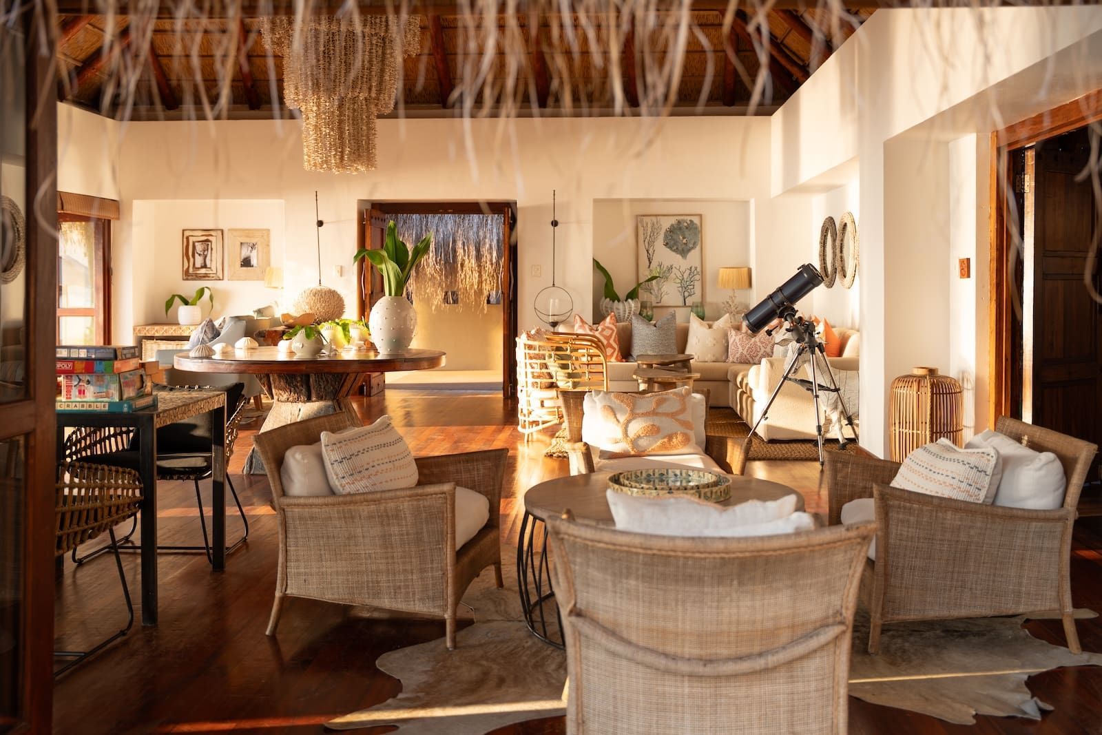 Cozy wicker seating area with warm lighting and a telescope overlooking a tropical view
