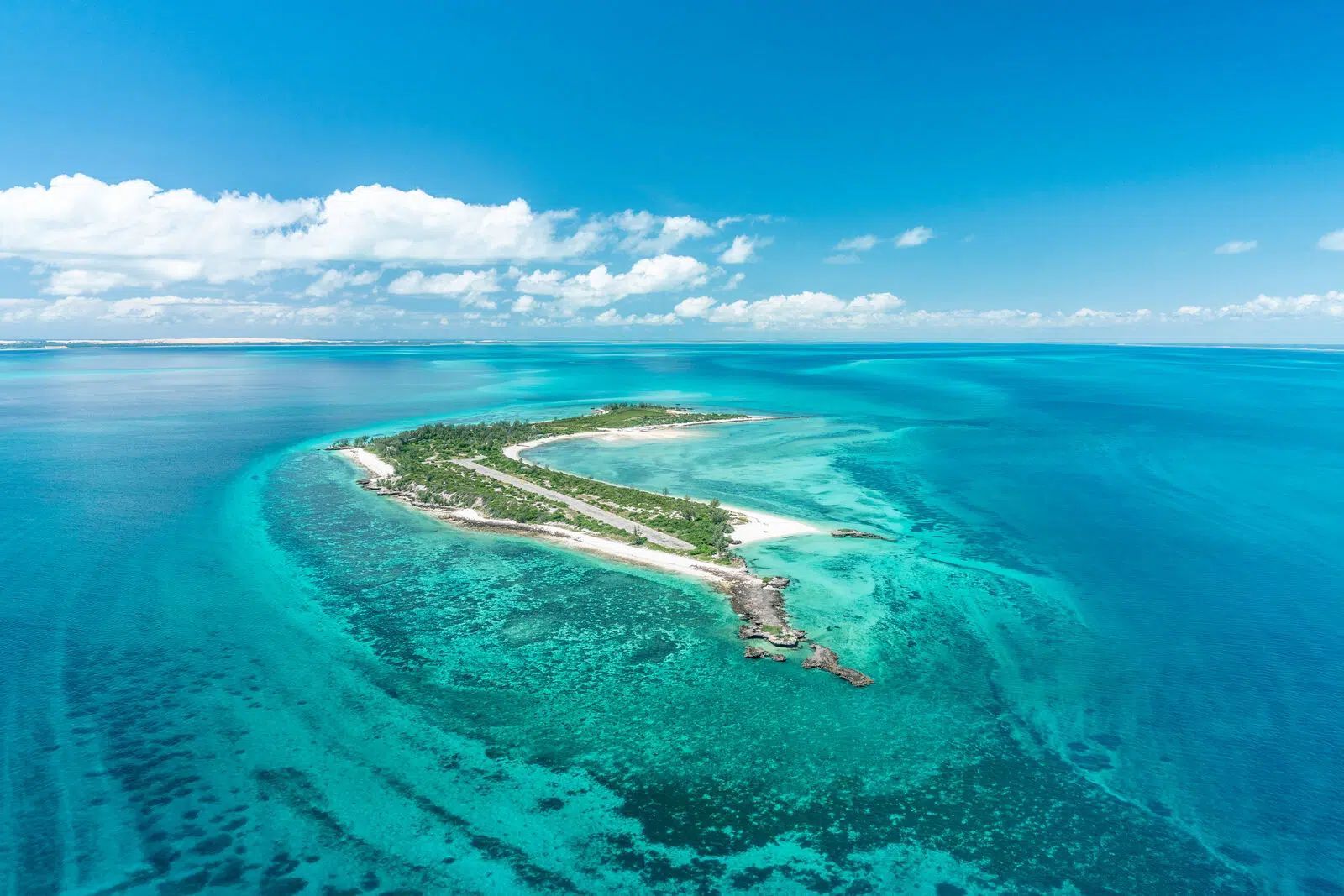 Aerial view of a small tropical island surrounded by bright turquoise ocean and white sand beaches.