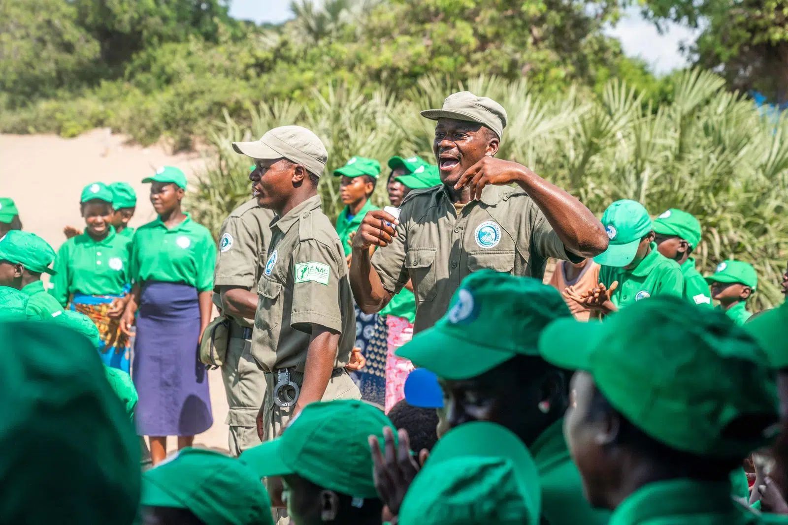 Uniformed group gathered outdoors; one man speaks into a microphone while others listen.