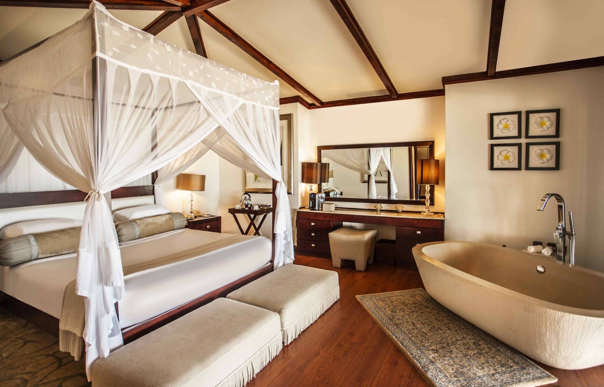 Luxury bedroom and bathroom suite with canopy bed, freestanding tub, and vanity mirror