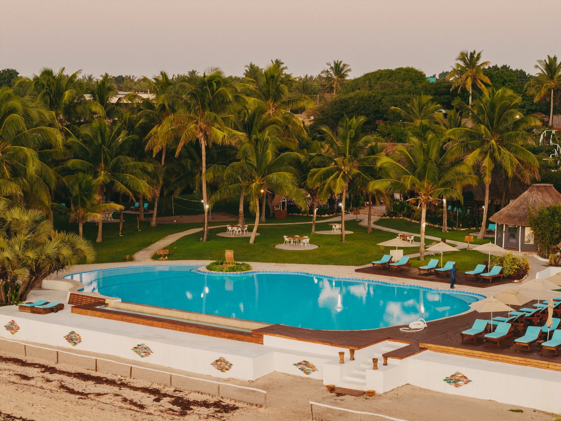 Resort pool surrounded by palm trees and lounge chairs in a tropical setting