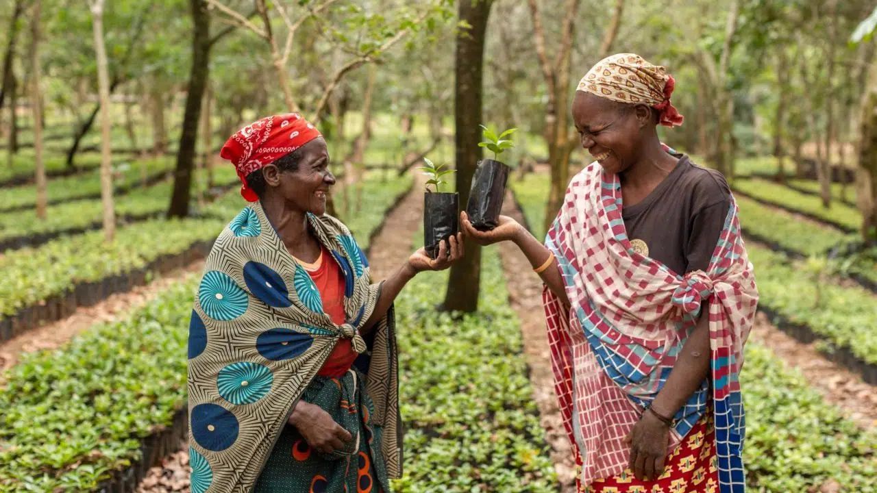 Two people in a crop field smiling and holding a smartphone together
