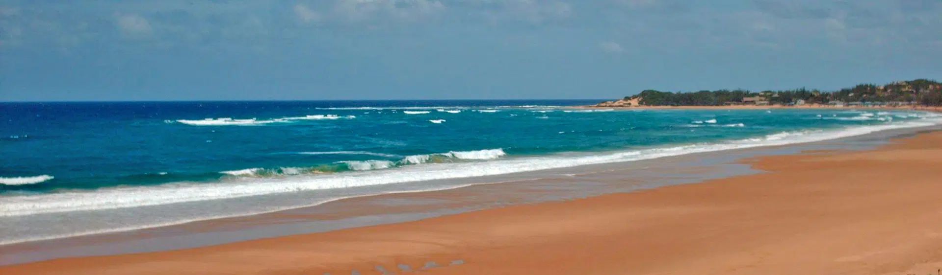 Sandy beach with turquoise waves and a blue sky along the shoreline