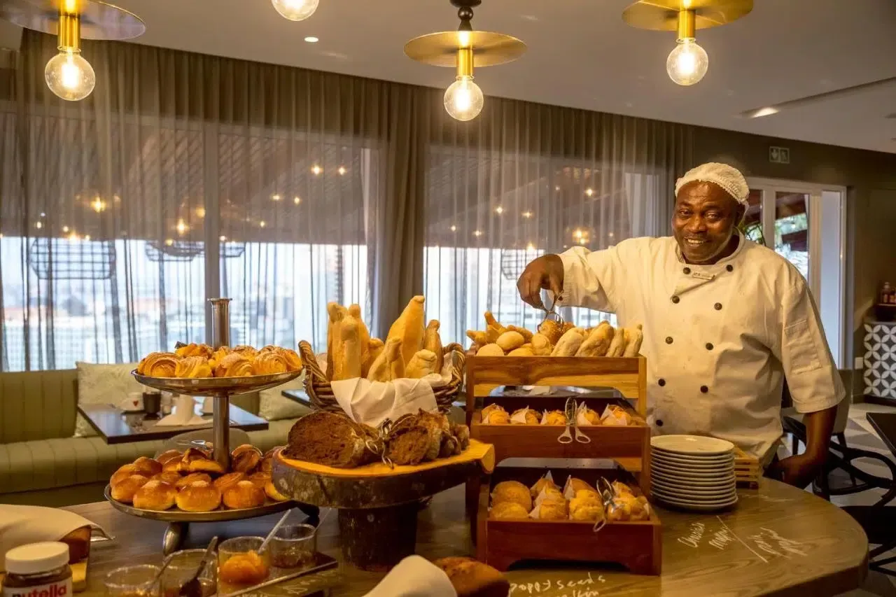 Chef serving food at a buffet table with assorted pastries and dishes in a warmly lit dining room