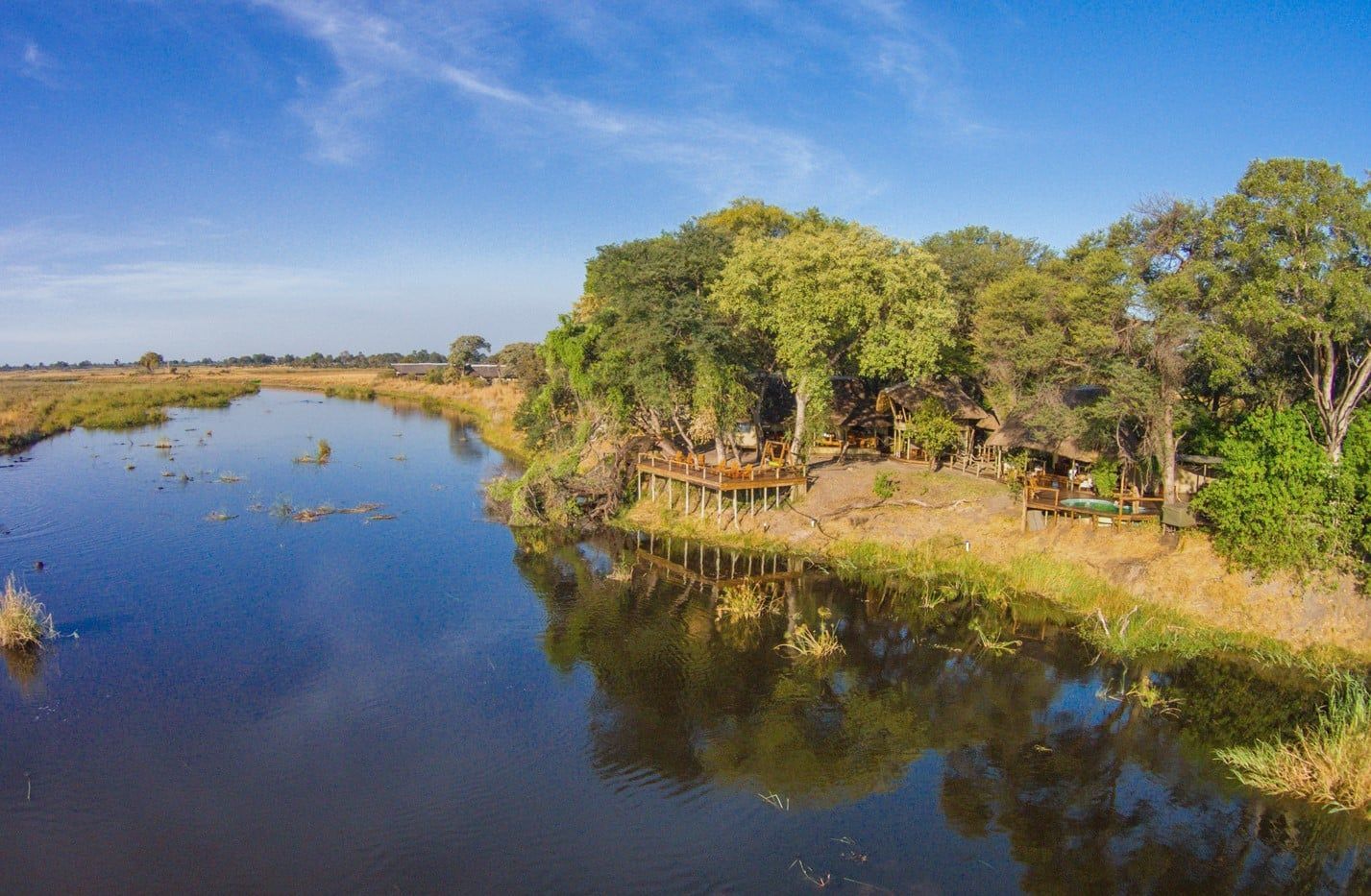Calm river reflecting trees and blue sky under a sunny landscape
