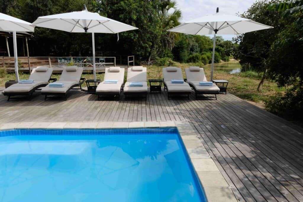 Poolside lounge chairs under white umbrellas beside a blue swimming pool