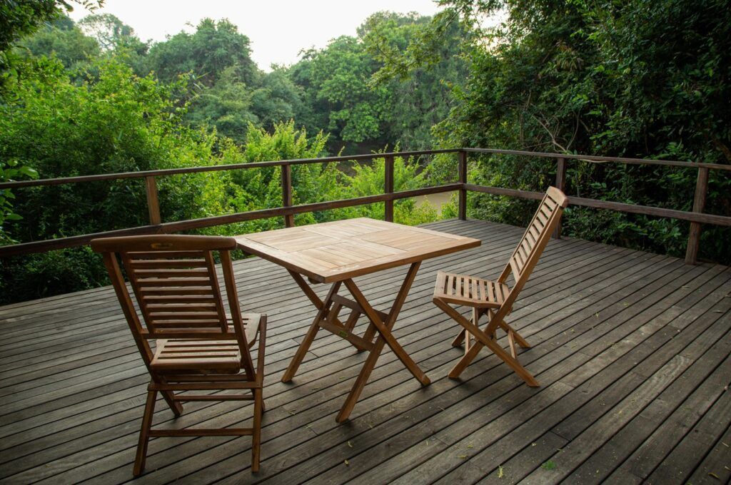 Wooden deck with table and chairs overlooking a lush green forest