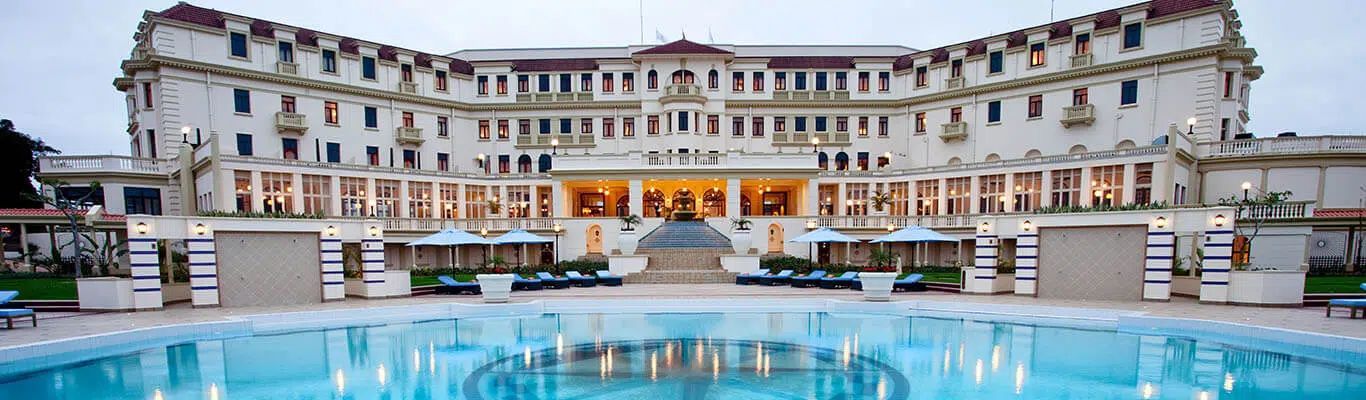 Luxurious hotel courtyard with a large blue pool and white lounge chairs at dusk